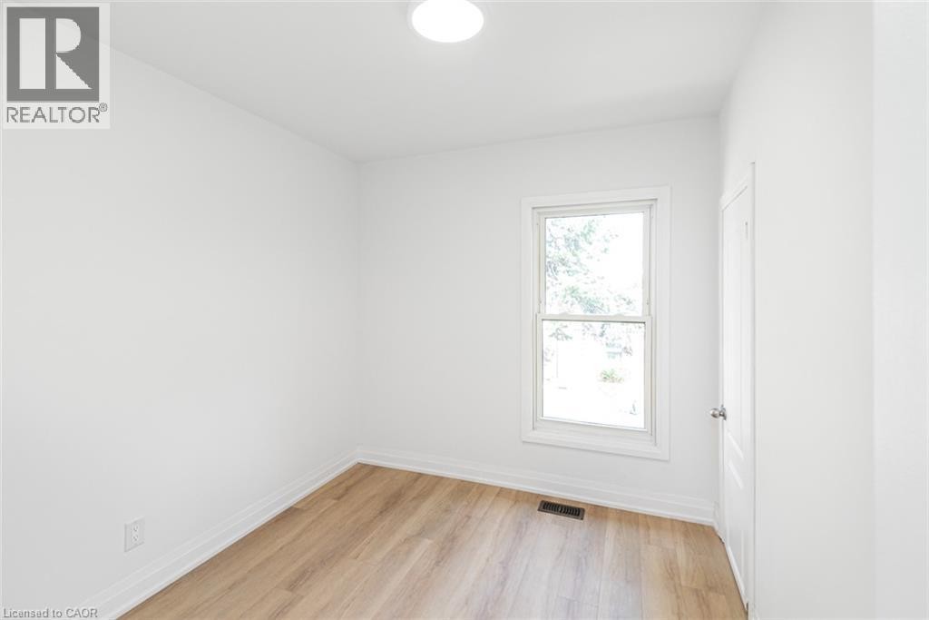 Bright room featuring a double-hung window, wood-finish flooring, and a flush-mount ceiling light - 90 Belview Avenue, Hamilton, ON