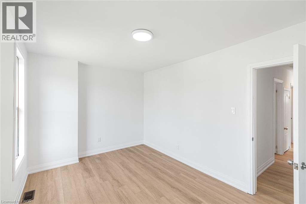 Light wood-finish flooring, white walls, flush mount ceiling light, and natural light from a single window - 90 Belview Avenue, Hamilton, ON