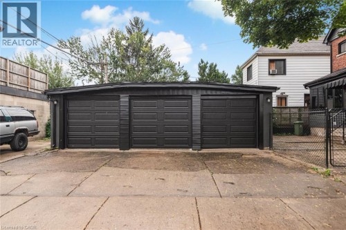Three-car detached garage with black panel doors and exterior lighting - 90 Belview Avenue, Hamilton, ON 