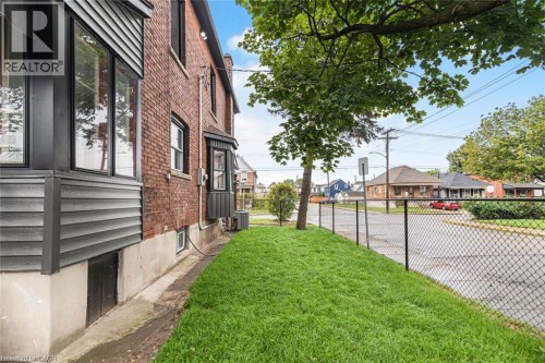 Brick exterior with dark-trimmed windows, a bay window, and a well-maintained lawn - 90 Belview Avenue, Hamilton, ON 