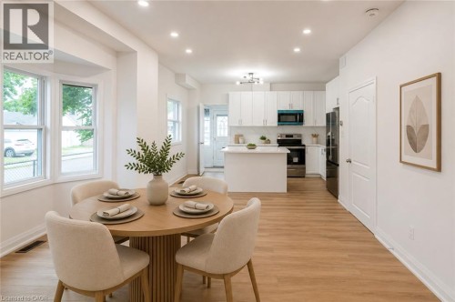 Recessed lighting, wood-finish flooring, bay window, white cabinetry, and a kitchen island with seating - 90 Belview Avenue, Hamilton, ON 