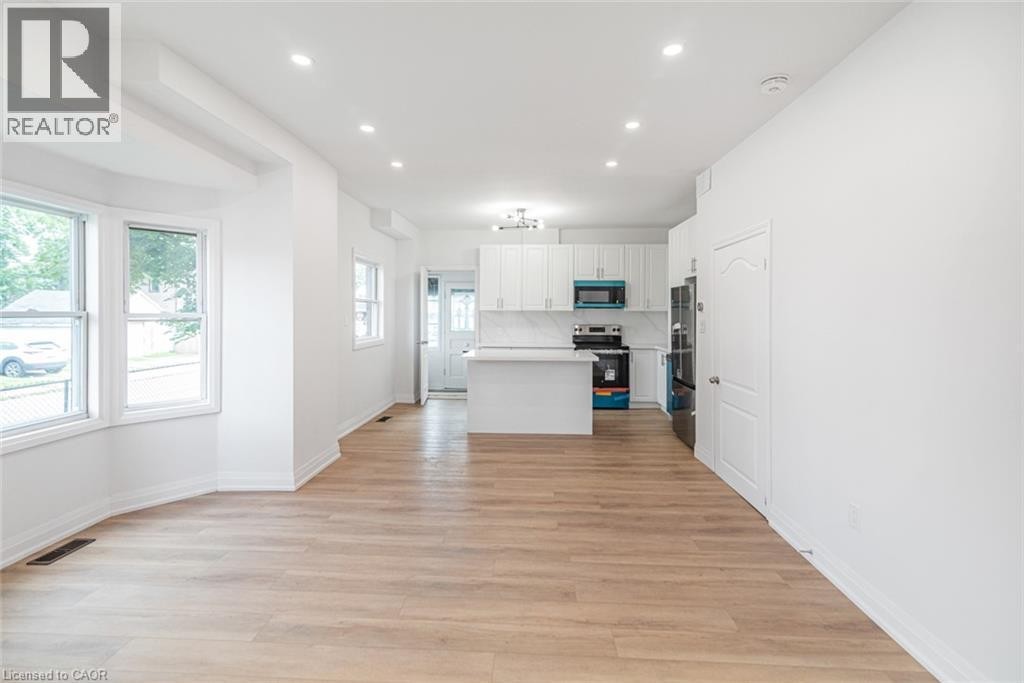 Open-concept living space featuring wood-finish flooring, recessed lighting, and a bay window - 90 Belview Avenue, Hamilton, ON