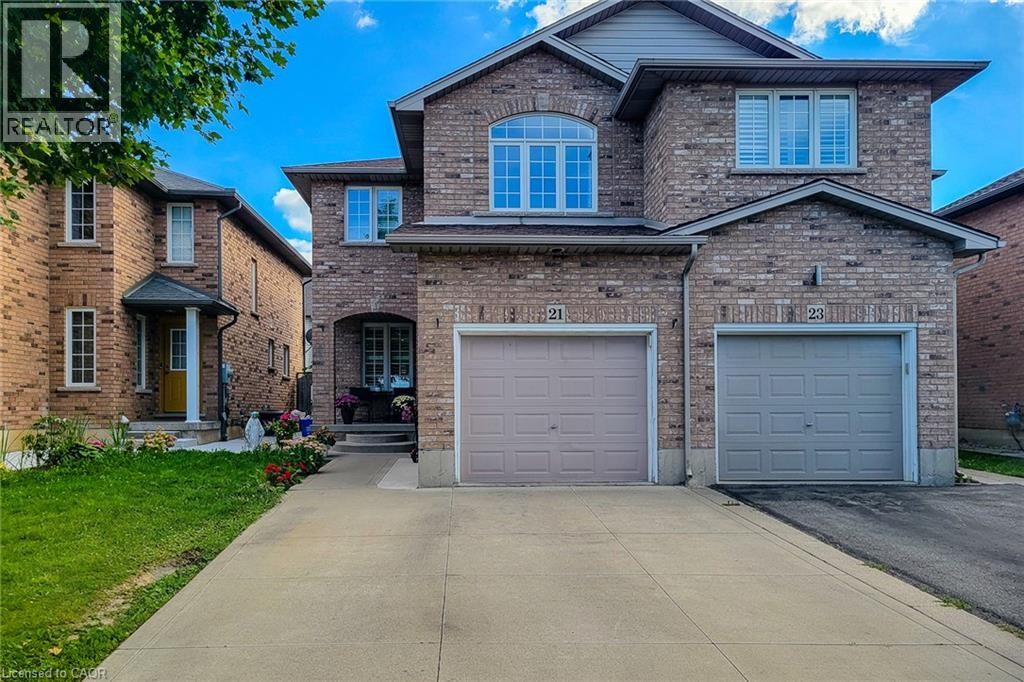 Brick exterior with multiple windows, two attached garages, and a paved driveway - 21 Jonathon Court, Hamilton, ON