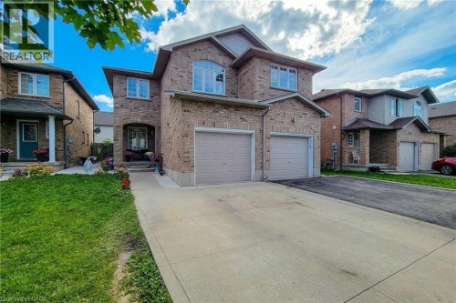 Brick exterior featuring an arched entryway, multiple windows with white trim, and a two-car garage - 21 Jonathon Court, Hamilton, ON 
