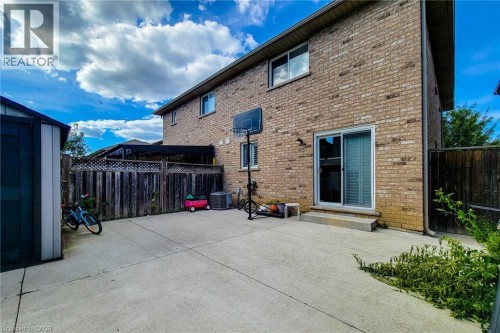 Brick exterior, concrete patio, sliding glass patio door, fenced perimeter, and storage shed - 21 Jonathon Court, Hamilton, ON 