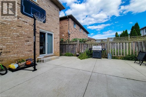 Concrete patio with a brick exterior, sliding glass door, and wood fence with lattice accents - 21 Jonathon Court, Hamilton, ON 