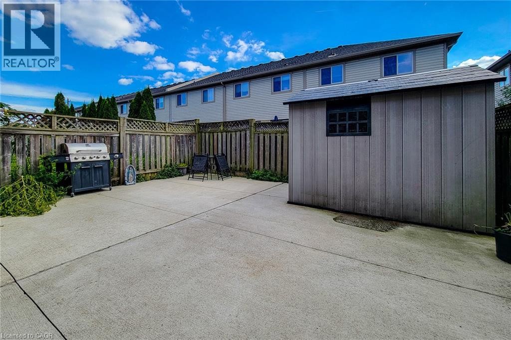 Concrete patio with wood fencing, lattice accents, and a built-in storage shed - 21 Jonathon Court, Hamilton, ON