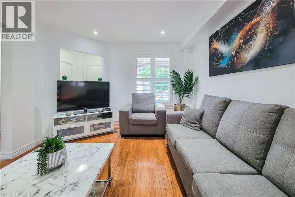 Hardwood flooring, recessed lighting, white window shutters, and a television console with built-in storage - 21 Jonathon Court, Hamilton, ON