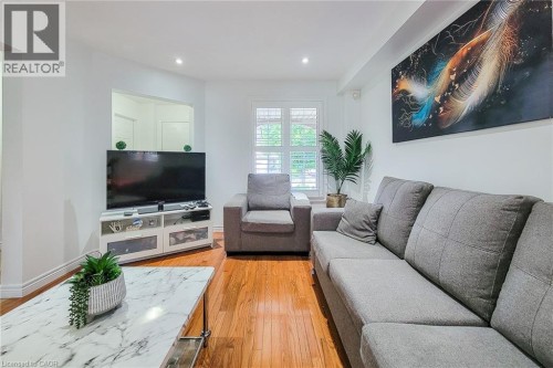 Hardwood flooring, recessed lighting, white window shutters, and a television console with built-in storage - 21 Jonathon Court, Hamilton, ON 