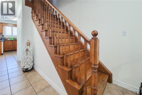 Hardwood staircase with turned balusters, tiled flooring, and light wall finishes - 21 Jonathon Court, Hamilton, ON 