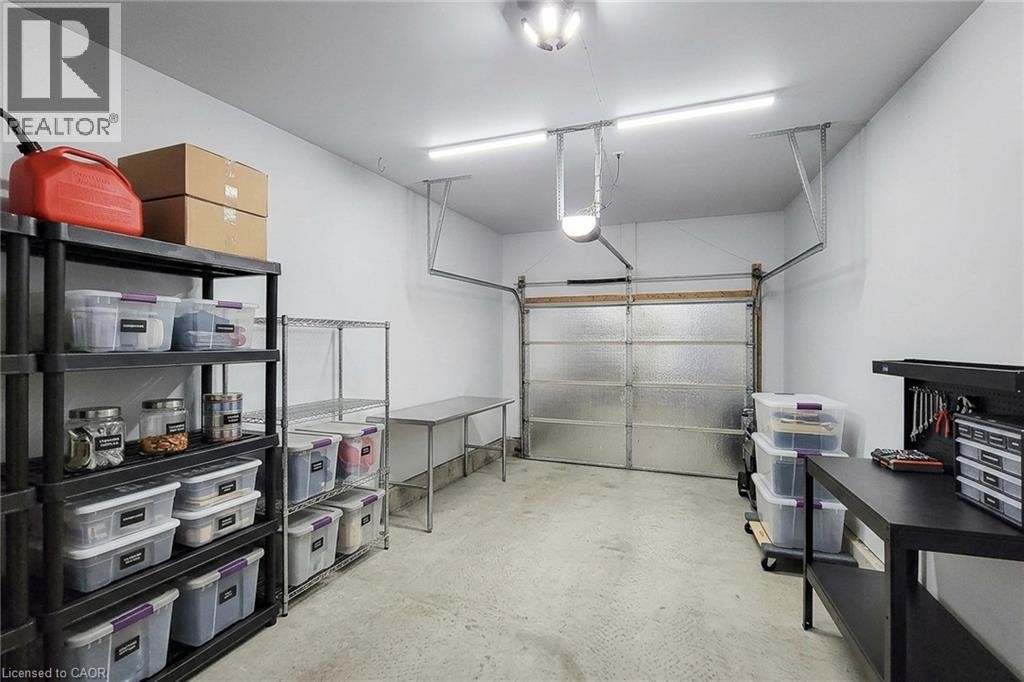 Attached garage with a textured overhead door, concrete flooring, and ceiling-mounted lighting - 21 Jonathon Court, Hamilton, ON