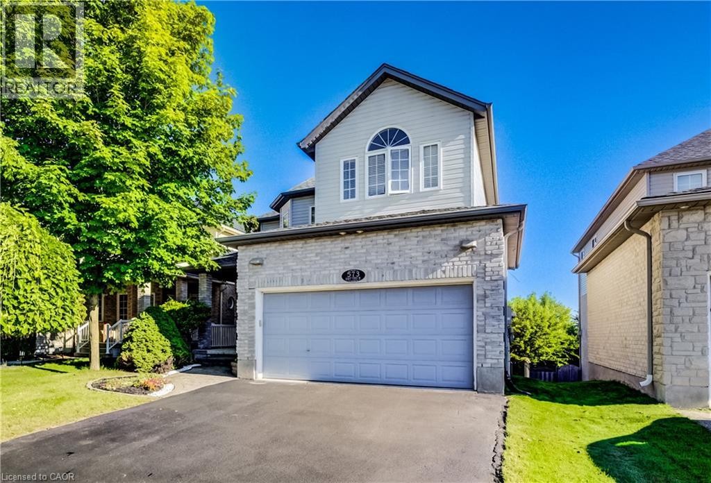 Two-story residence featuring a stone and siding exterior, an integrated garage, an arched window on the upper level, and a paved driveway - 573 Robert Ferrie Drive, Kitchener, ON