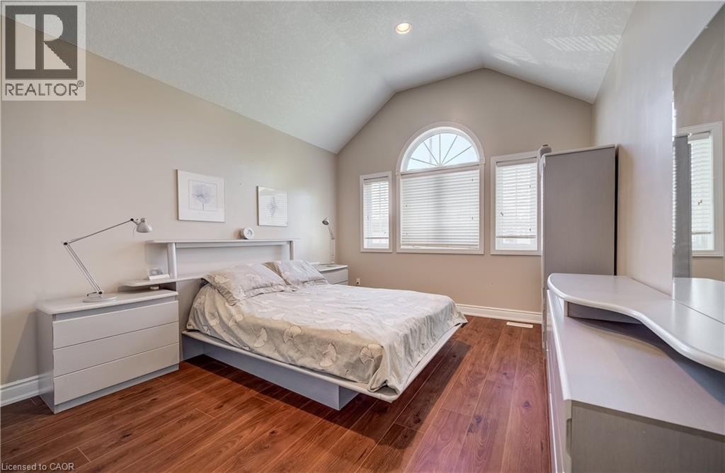 Vaulted ceiling, wood-finish flooring, arched window, two additional windows, and a built-in headboard storage - 573 Robert Ferrie Drive, Kitchener, ON