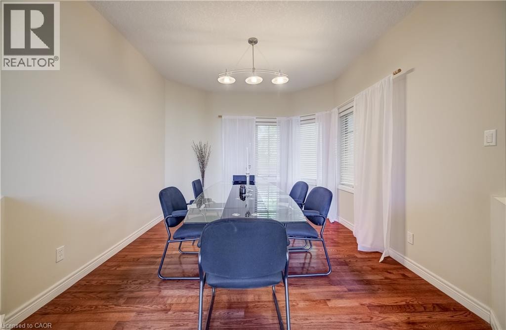 Bay window with white blinds and sheer curtains, wood-finish flooring, and a contemporary ceiling light fixture - 573 Robert Ferrie Drive, Kitchener, ON