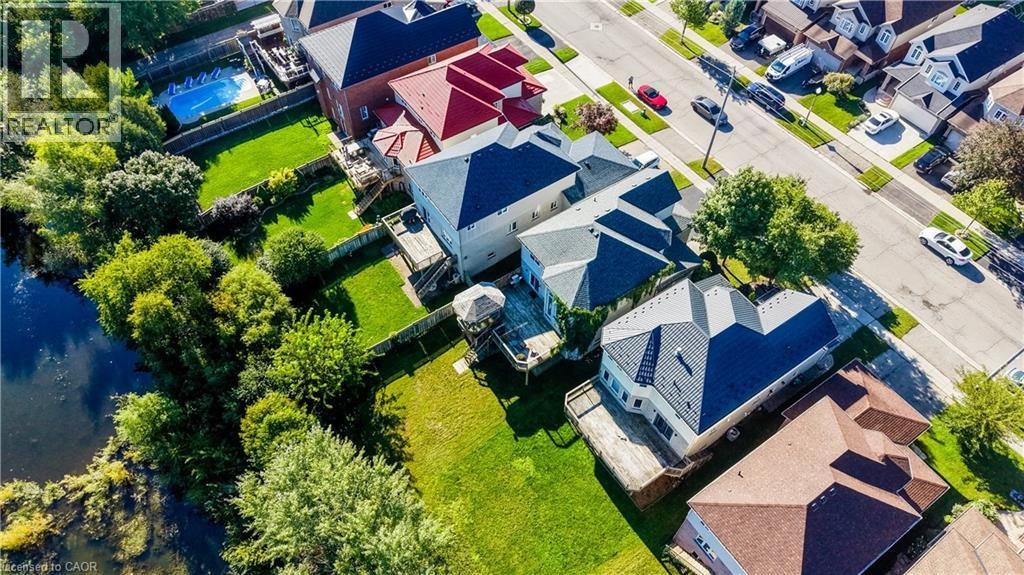 Expansive property featuring a tranquil water element, lush green landscaping, and multiple private wooden decks - 573 Robert Ferrie Drive, Kitchener, ON