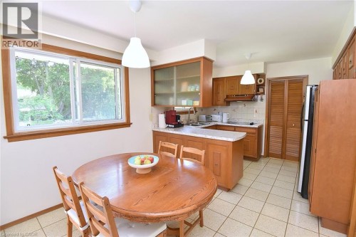 Wood-finish cabinetry with glass-front accents, light-toned countertop, and tiled backsplash - 372 Fennell Avenue W, Hamilton, ON 