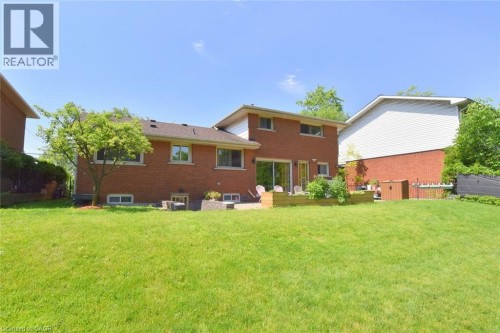 Expansive grassy yard with a brick exterior, a wood deck, and a sliding glass door - 372 Fennell Avenue W, Hamilton, ON 
