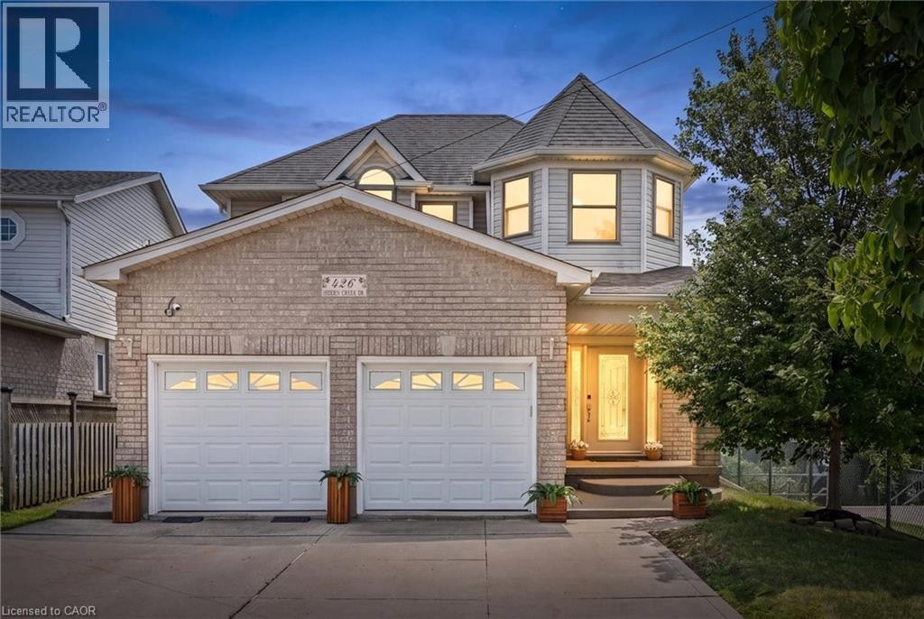 Brick facade featuring a double garage, architectural turret, and a covered entry with a decorative glass door - 426 Hidden Creek Drive, Kitchener, ON