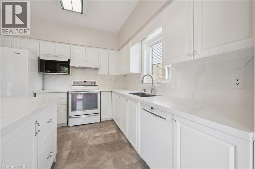 Kitchen featuring white cabinetry, white countertops, stainless steel appliances, a double basin sink, and a skylight - 426 Hidden Creek Drive, Kitchener, ON