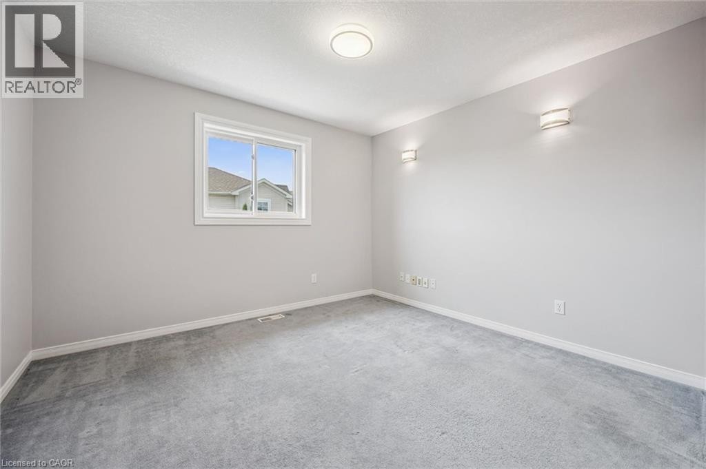 Carpeted room with a double-pane window, flush-mount ceiling light, and two wall sconces - 426 Hidden Creek Drive, Kitchener, ON