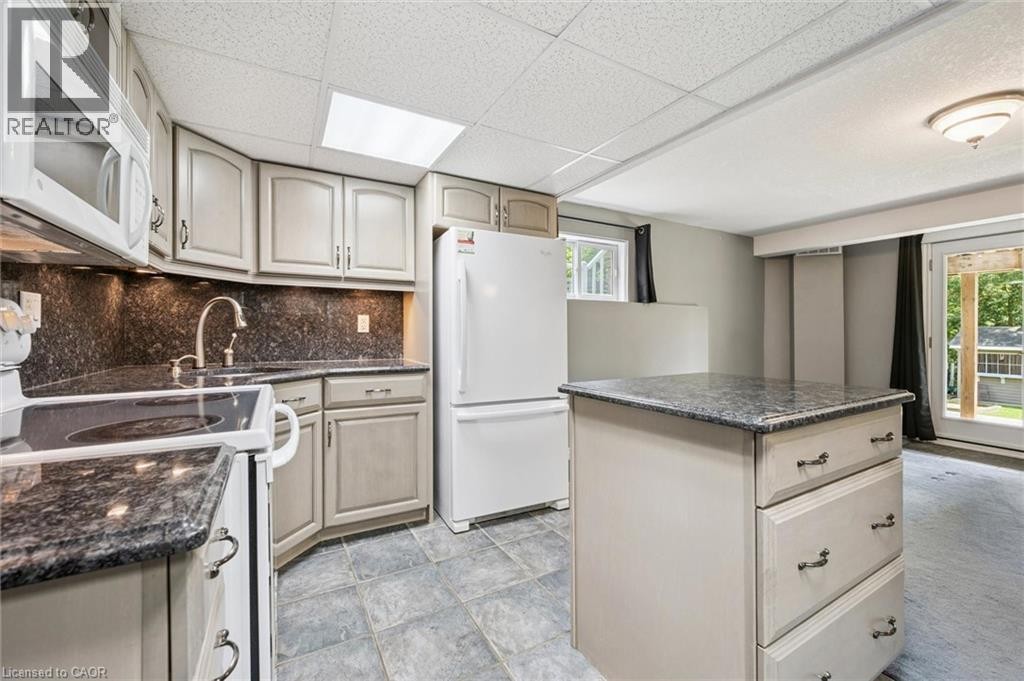 Kitchen featuring a functional island, white appliances, under-cabinet lighting, and a sliding glass door - 426 Hidden Creek Drive, Kitchener, ON