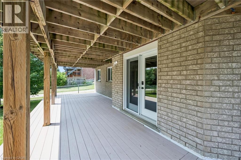 Expansive covered patio featuring wood support posts, wood-finish decking, and a brick exterior wall with sliding glass doors - 426 Hidden Creek Drive, Kitchener, ON