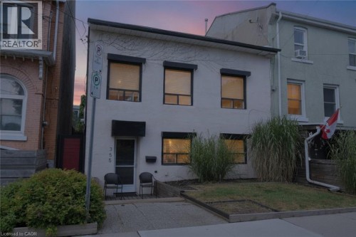 White facade with black window trim, front entry with awning, and integrated front door - 355 Macnab Street N, Hamilton, ON 