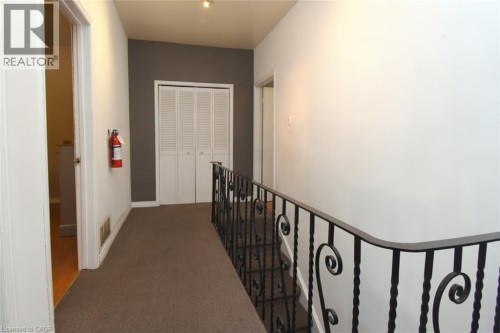 Carpeted hallway with a bi-fold closet, a black wrought iron railing, and recessed lighting - 355 Macnab Street N, Hamilton, ON 