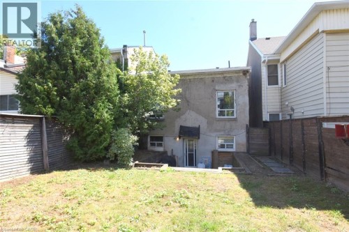 Expansive grassy yard area with perimeter fencing, mature trees, and a stucco exterior - 355 Macnab Street N, Hamilton, ON 
