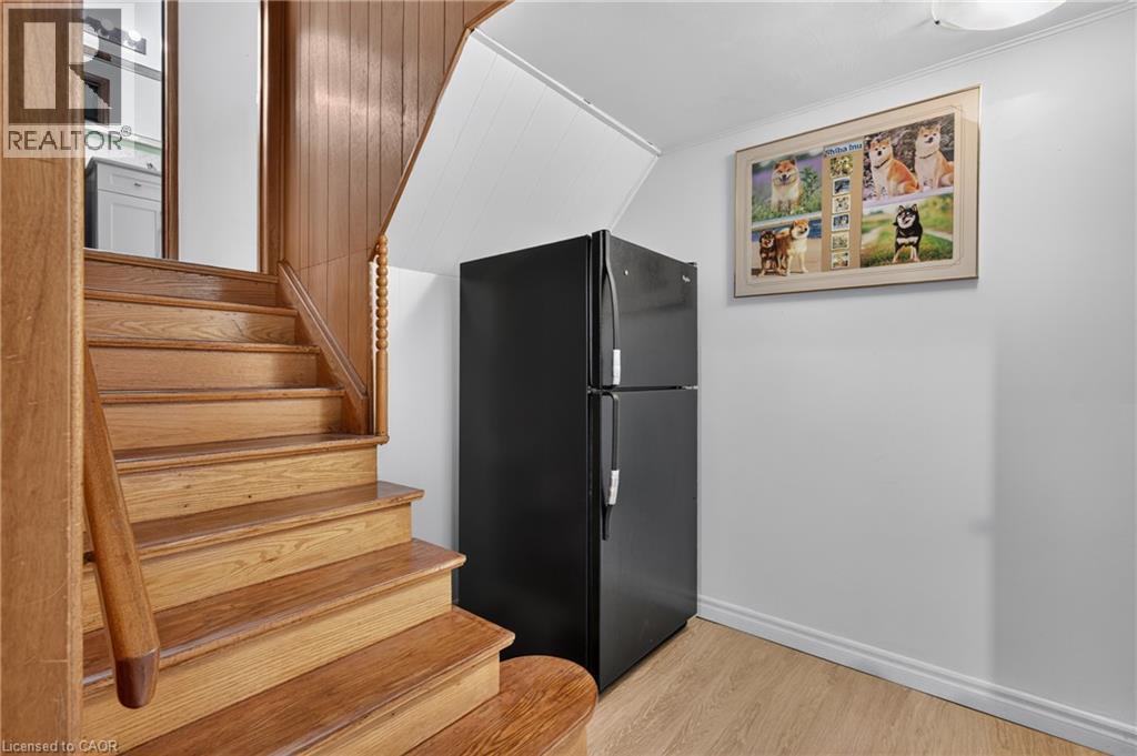 Wood staircase with spindle newel post, wood-finish flooring, and white walls - 114 Shuh Avenue, Kitchener, ON