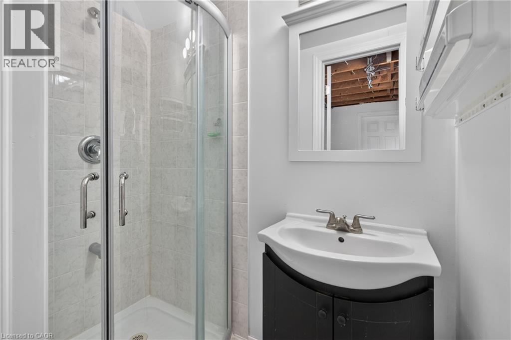 Enclosed shower with clear glass doors, white tiled walls, and a white shower base - 114 Shuh Avenue, Kitchener, ON