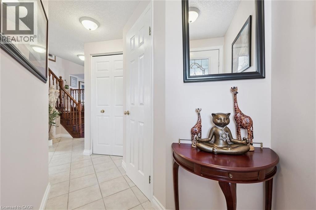 Tiled flooring throughout the entry, rich wood staircase with balusters, flat-panel interior doors, and flush-mount ceiling lighting - 86 Bridlewreath Street, Kitchener, ON