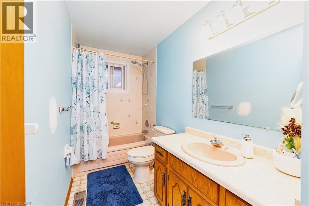 Bathroom featuring a single vanity with wood-finish cabinetry, a built-in sink, and a framed mirror - 41 Tuerr Drive, Kitchener, ON