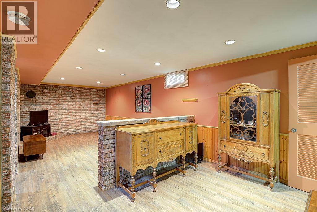 Recessed lighting, wood-finish flooring, exposed brick accent wall, wainscoting, and a built-in partial wall - 210 Shelley Drive, Kitchener, ON