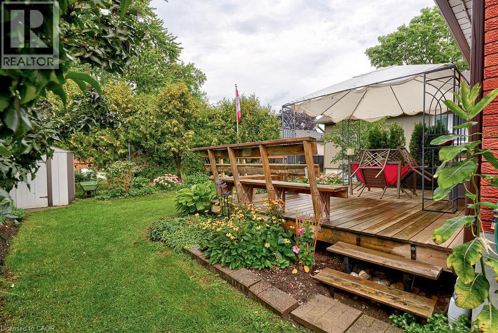 Expansive backyard featuring a wood deck, built-in benches, and garden beds - 210 Shelley Drive, Kitchener, ON