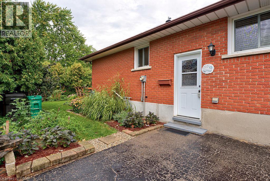 Red brick exterior featuring white trim windows and a white entry door - 210 Shelley Drive, Kitchener, ON