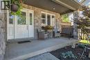 Covered front porch featuring stone-clad pillars, a white main entry door with glass inserts, and a wide concrete surface - 125 Langlaw Drive, Cambridge, ON 
