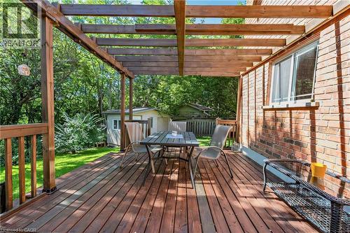 Spacious wooden deck with an integrated wood pergola, featuring a brick exterior wall and a window - 125 Langlaw Drive, Cambridge, ON 