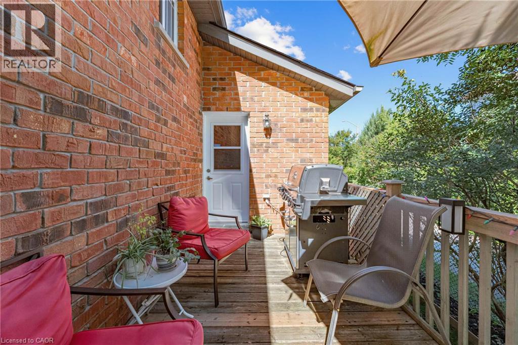 Wood deck with a brick exterior, white exterior door, and wood railing - 125 Langlaw Drive, Cambridge, ON
