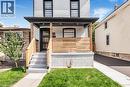 White brick facade with black trim windows, covered front porch with wood railings, modern front entry door, and concrete steps - 250 Rosslyn Avenue N, Hamilton, ON 