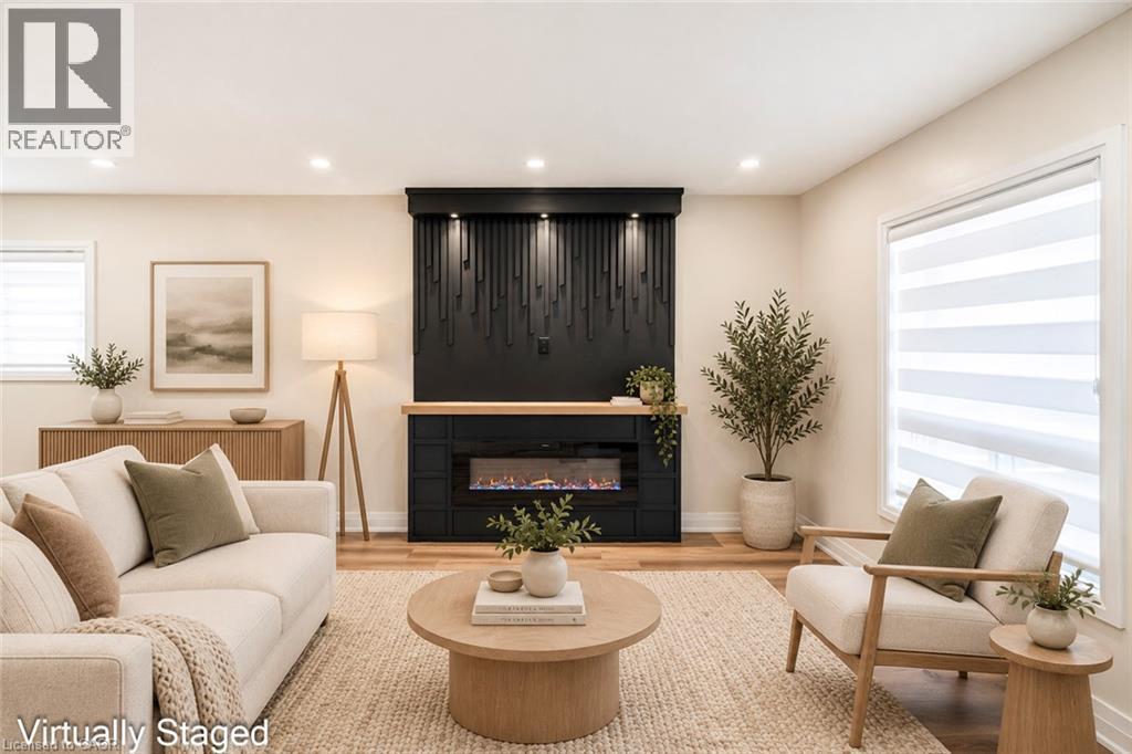 Modern fireplace with a decorative mantel, wood-finish flooring, recessed lighting, and large windows - 250 Rosslyn Avenue N, Hamilton, ON