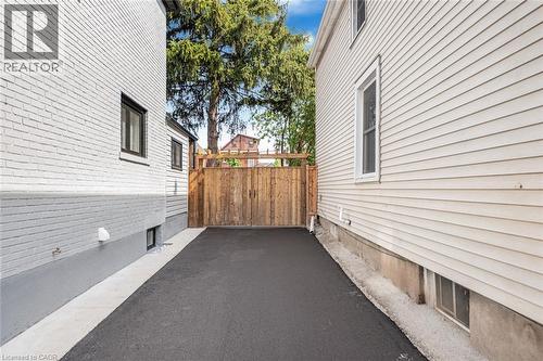 Paved driveway with a wood fence and white brick exterior - 250 Rosslyn Avenue N, Hamilton, ON 