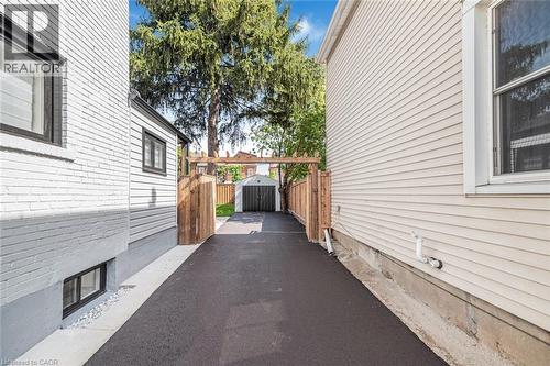 Paved driveway with wood fencing, leading to a detached garage - 250 Rosslyn Avenue N, Hamilton, ON 