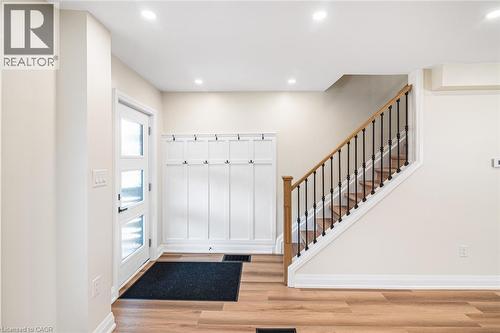 Entryway featuring wood-finish flooring, a contemporary front door with multiple glass panes, recessed lighting, and a built-in wall panel with hooks - 250 Rosslyn Avenue N, Hamilton, ON 