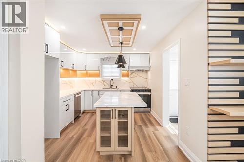 Open-concept kitchen with wood-finish flooring, white cabinetry, and a central island - 250 Rosslyn Avenue N, Hamilton, ON 