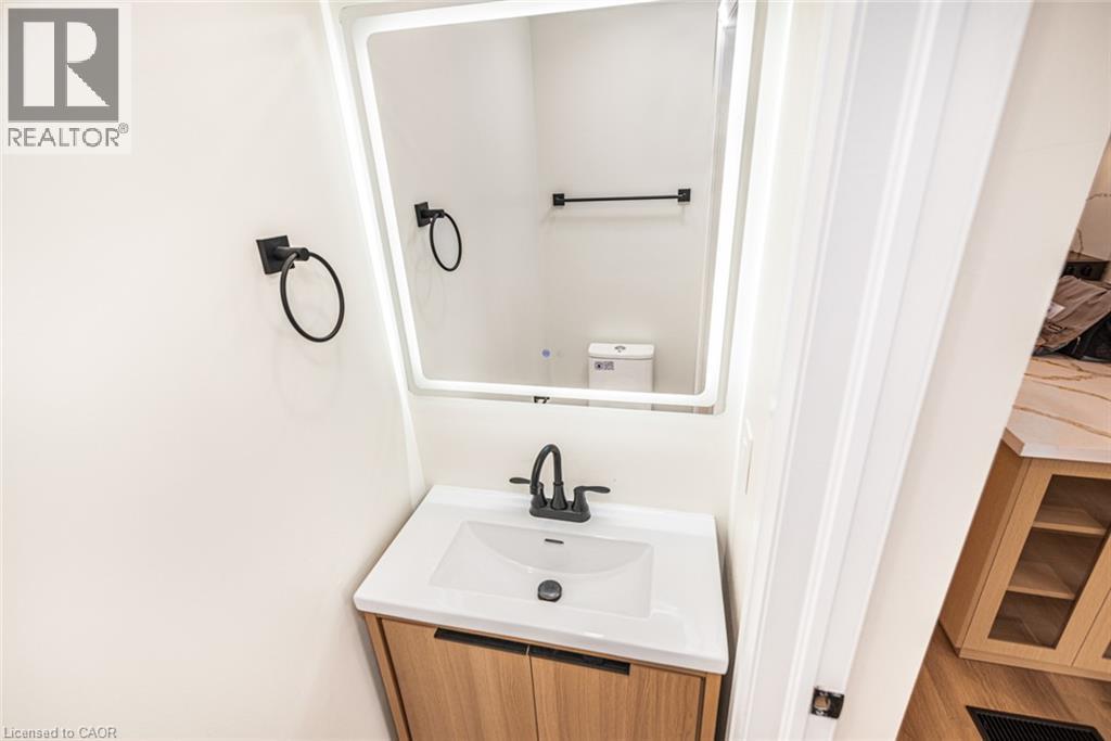 Wood-finish vanity with an integrated sink, white countertop, and matte black faucet - 250 Rosslyn Avenue N, Hamilton, ON