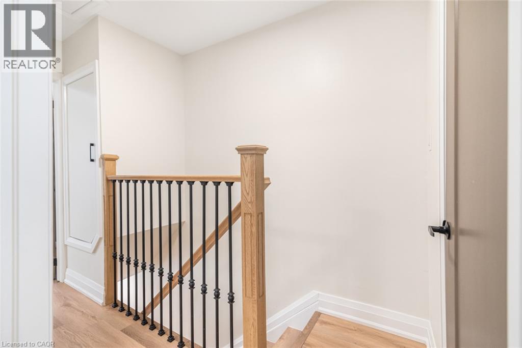 Wood-finish flooring, staircase with wood newel posts, and wrought iron balusters - 250 Rosslyn Avenue N, Hamilton, ON