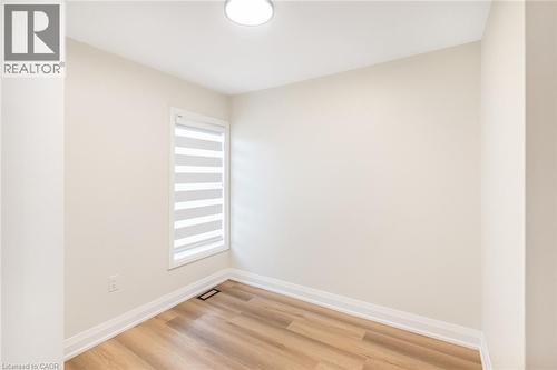 Wood-finish flooring, neutral wall paint, window with horizontal blinds, flush mount ceiling light - 250 Rosslyn Avenue N, Hamilton, ON 