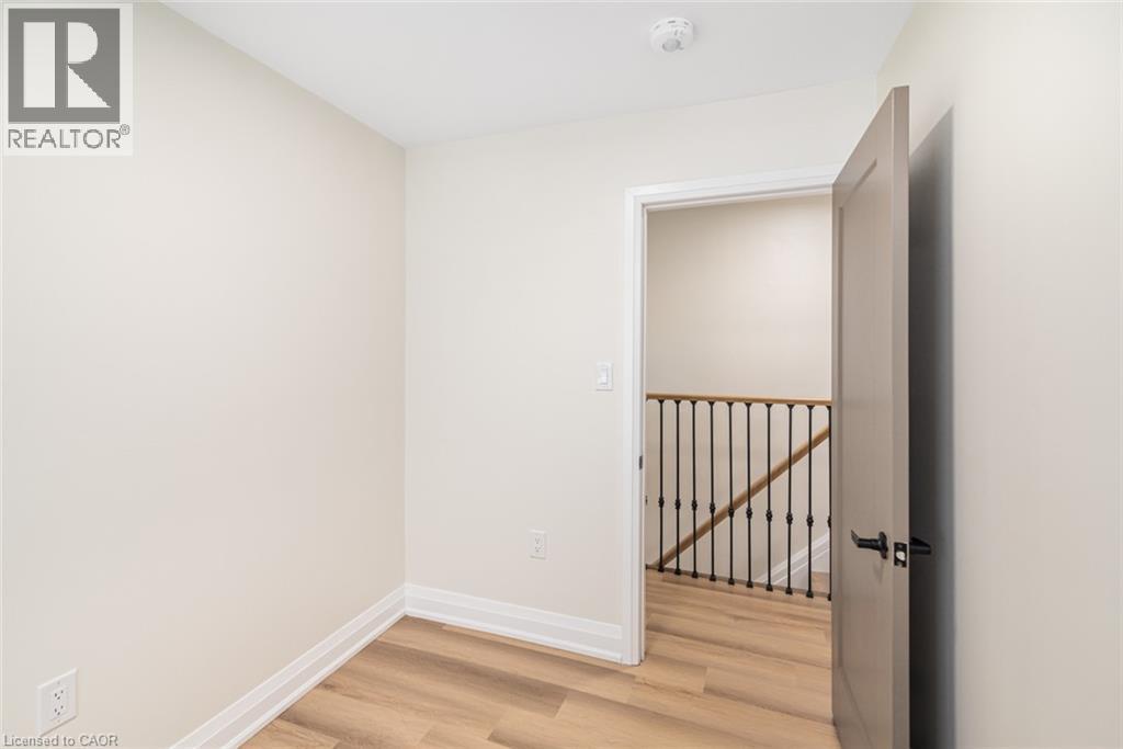 Light wood-finish flooring, neutral wall paint, and a modern interior door with dark hardware - 250 Rosslyn Avenue N, Hamilton, ON