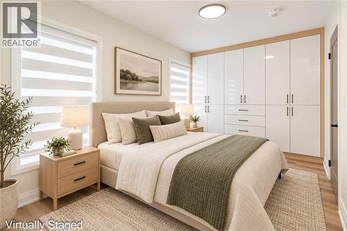 Integrated white gloss cabinetry with wood-finish trim, two large windows with horizontal blinds, and wood-finish flooring - 250 Rosslyn Avenue N, Hamilton, ON 